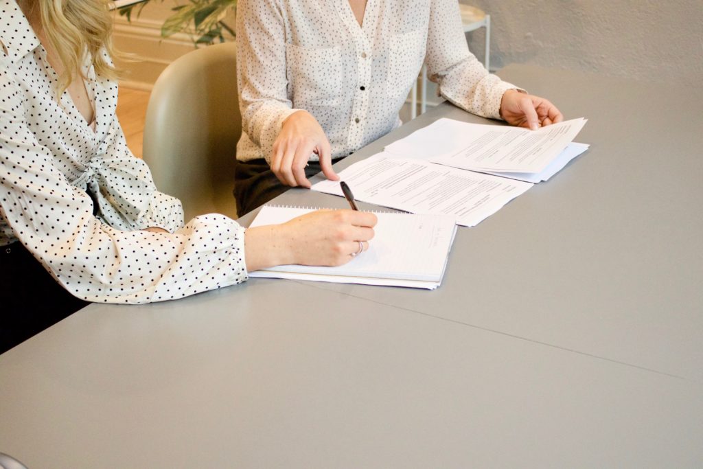 Two women sitting at table with documents