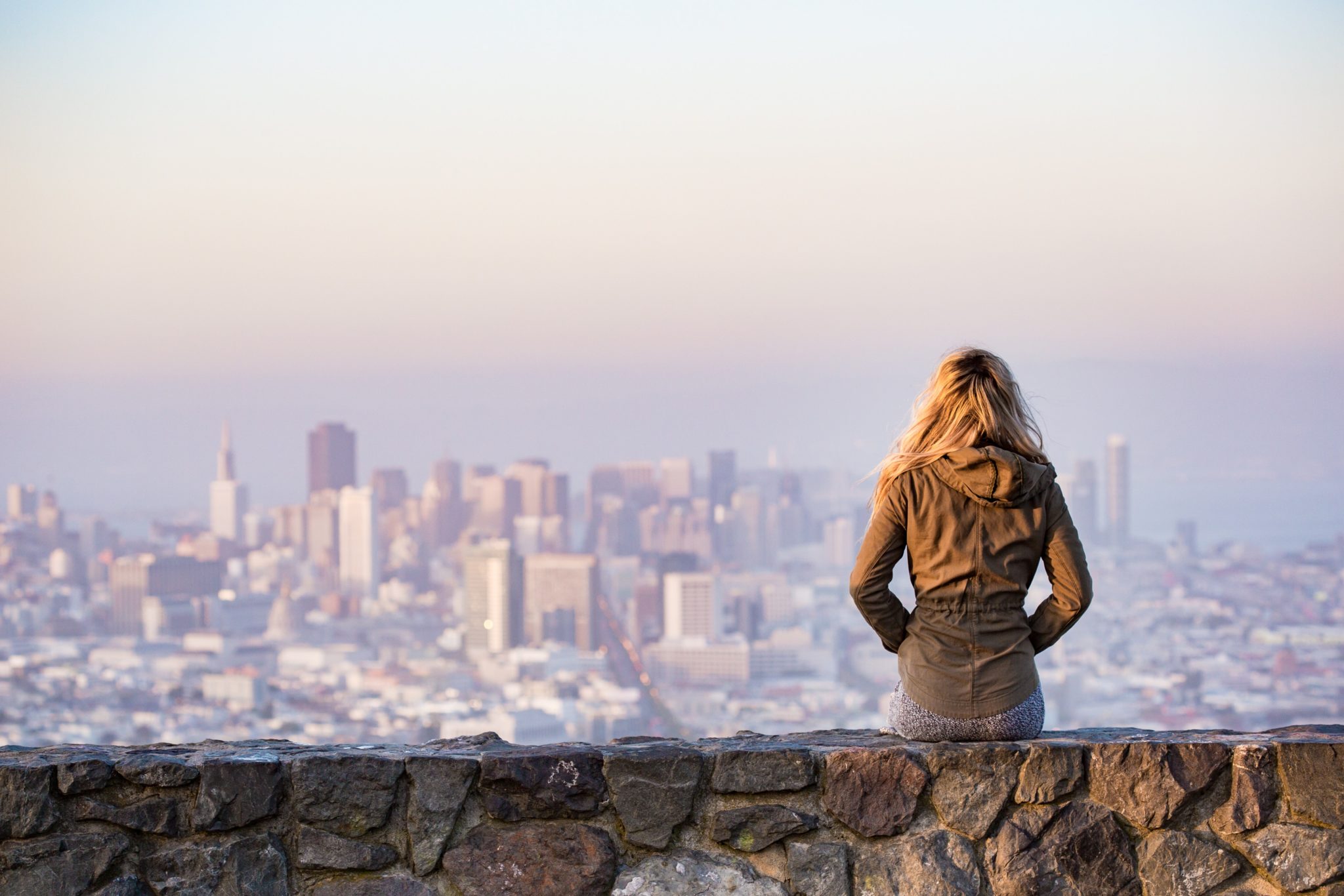 woman sitting on rock overlooking city